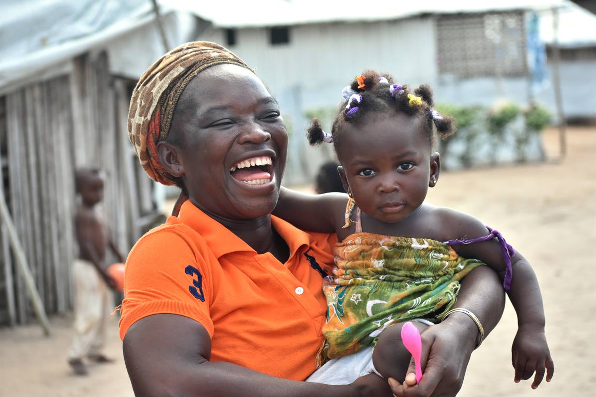 Josiane Bahi, 33 ans, tient dans ses bras sa petite-fille Grâce Debra de 1 an, dans le camp de réfugiés ivoiriens d'Ampain (Ghana), où Josiane Bahi, une Méthodiste Unie, réside depuis 2012. Sa petite-fille faisait partie des plus de 540 enfants qui ont reçu un présent de l'Église Méthodiste Unie de Côte d'Ivoire le jour de Noël. Photo de Isaac Broune, UM News.